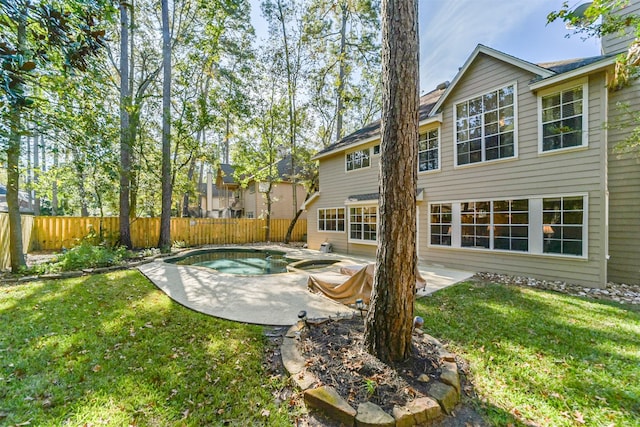 back of property with a lawn, a patio area, and a fenced in pool