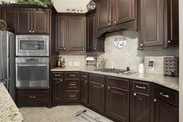 kitchen with backsplash, dark brown cabinets, light tile patterned flooring, light stone counters, and stainless steel appliances