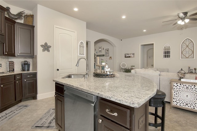 kitchen featuring dishwasher, sink, a kitchen island with sink, a breakfast bar, and dark brown cabinets