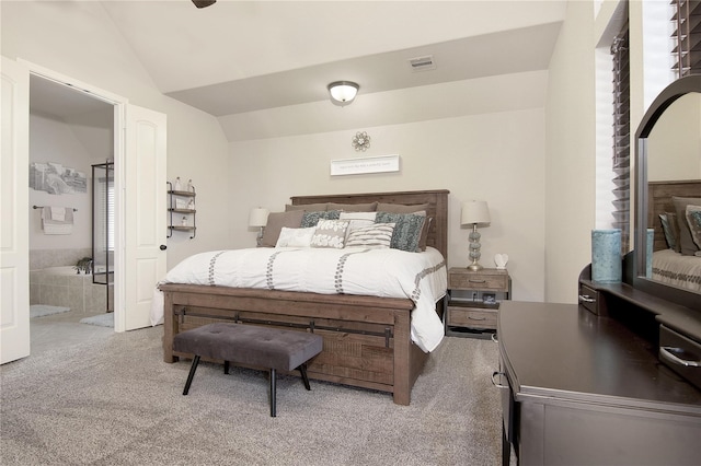 carpeted bedroom with ensuite bathroom and lofted ceiling