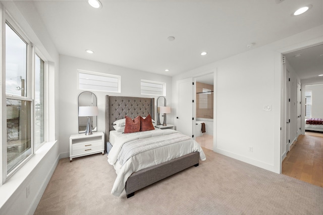 bedroom featuring light colored carpet, connected bathroom, and multiple windows