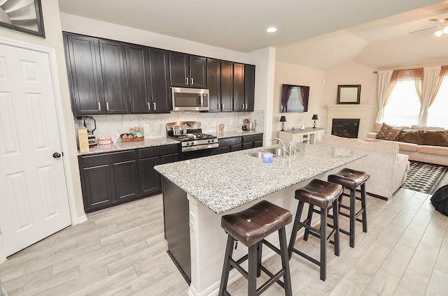 kitchen featuring sink, stainless steel appliances, a kitchen breakfast bar, an island with sink, and decorative backsplash