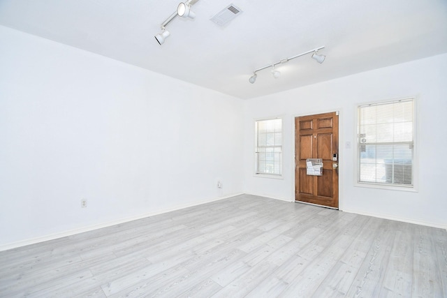 spare room featuring rail lighting and light hardwood / wood-style floors