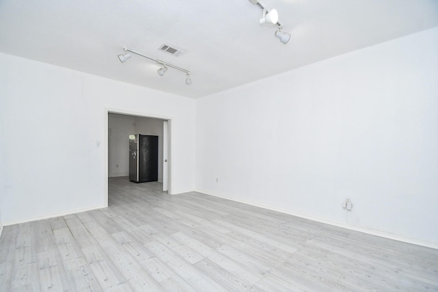 empty room with light hardwood / wood-style flooring and rail lighting