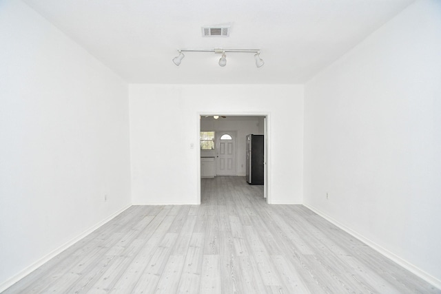 empty room with light hardwood / wood-style floors and track lighting