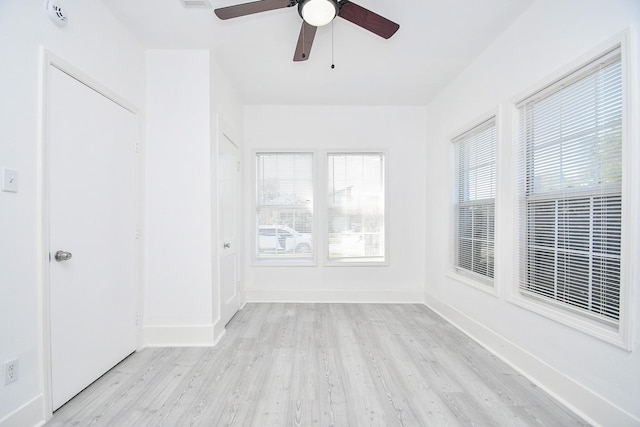 spare room featuring ceiling fan, light hardwood / wood-style floors, and a wealth of natural light