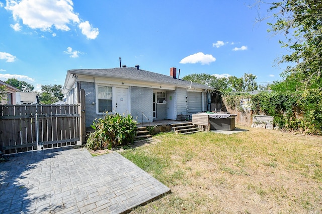 rear view of house with a yard, a patio, and a hot tub