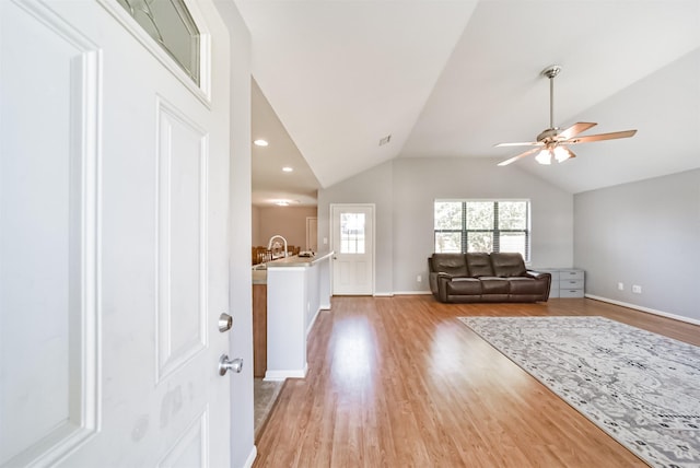 unfurnished living room with ceiling fan, lofted ceiling, and light wood-type flooring