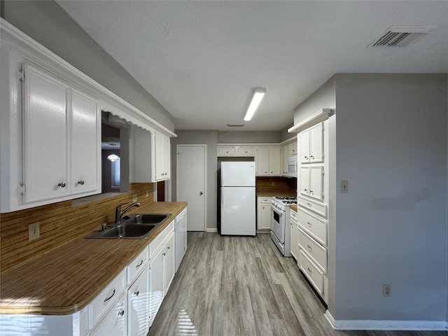 kitchen with light wood-type flooring, backsplash, white appliances, sink, and white cabinets