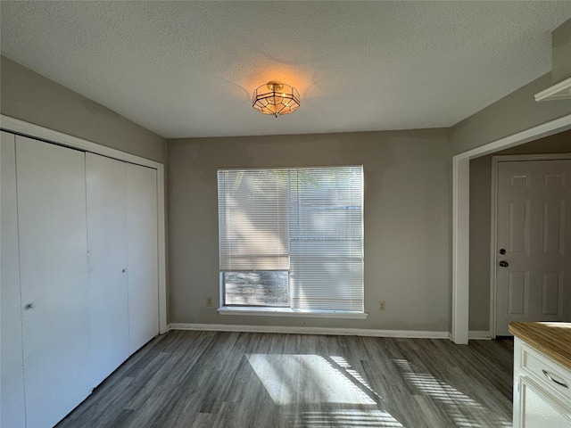 unfurnished bedroom with dark hardwood / wood-style flooring, a textured ceiling, and a closet