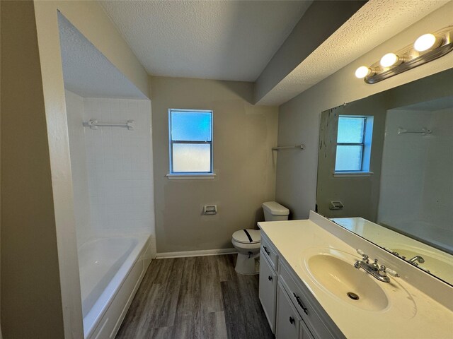 bathroom featuring toilet, a healthy amount of sunlight, a textured ceiling, and wood-type flooring