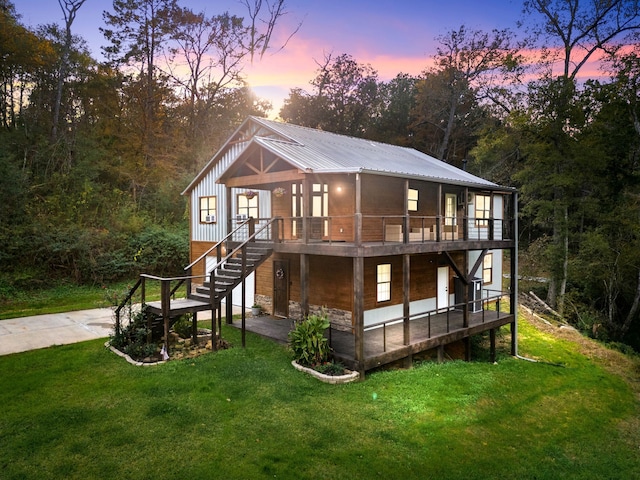 back house at dusk featuring a lawn