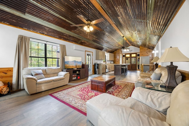 living room featuring ceiling fan, lofted ceiling with beams, an AC wall unit, wood walls, and light wood-type flooring