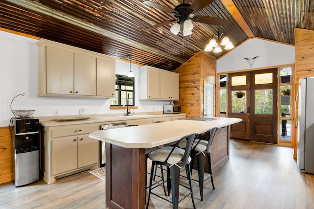 kitchen featuring stainless steel appliances, cream cabinets, a kitchen island, and light hardwood / wood-style floors