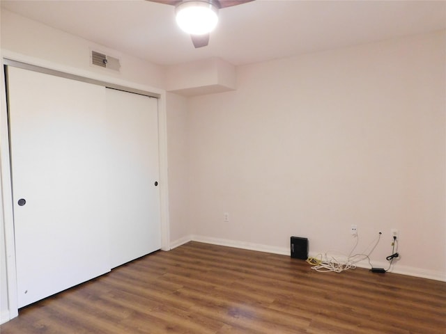 unfurnished bedroom featuring ceiling fan, a closet, and dark wood-type flooring