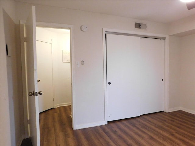 unfurnished bedroom featuring a closet and dark hardwood / wood-style flooring