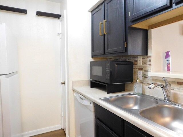 kitchen with decorative backsplash, dark hardwood / wood-style flooring, white appliances, and sink