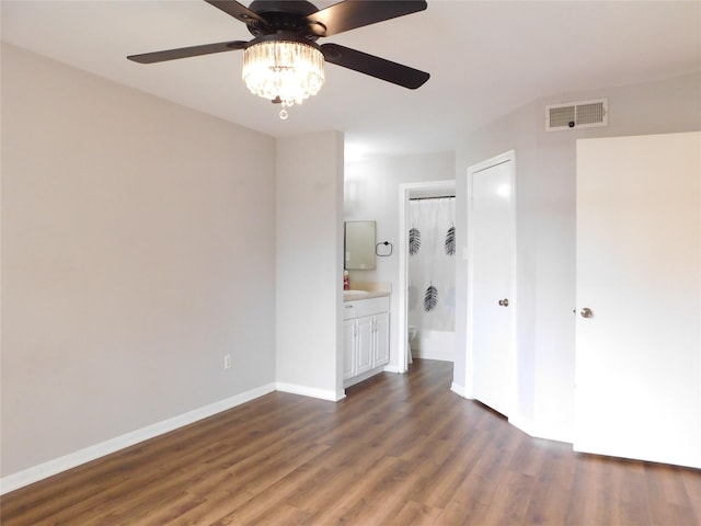 unfurnished bedroom with ceiling fan, a closet, dark wood-type flooring, and ensuite bath