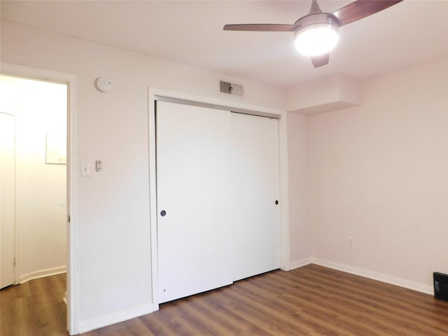 unfurnished bedroom featuring ceiling fan, dark wood-type flooring, and a closet