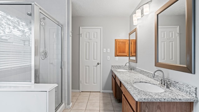 bathroom with a textured ceiling, vanity, tile patterned floors, and a shower with shower door