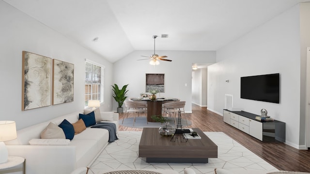 living room featuring ceiling fan, vaulted ceiling, and light wood-type flooring