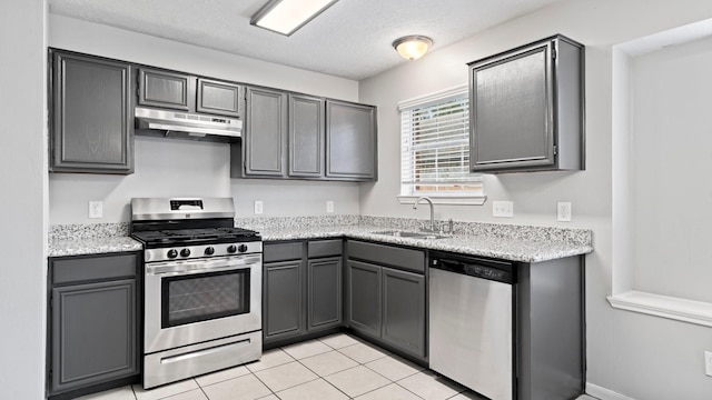 kitchen featuring gray cabinetry, sink, light tile patterned flooring, light stone counters, and stainless steel appliances