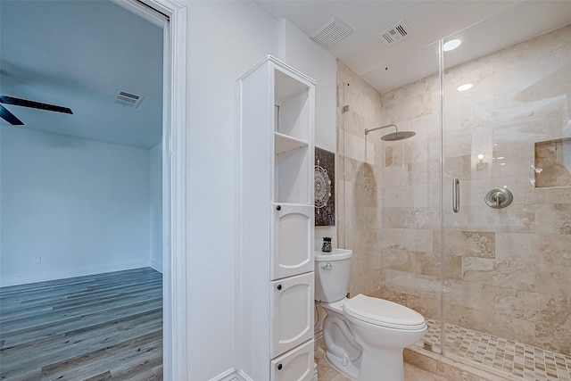 bathroom with hardwood / wood-style floors, toilet, a shower with door, and ceiling fan