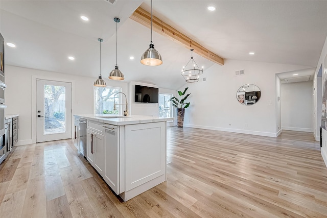 kitchen featuring sink, hanging light fixtures, lofted ceiling with beams, an island with sink, and light hardwood / wood-style floors