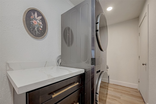 laundry area featuring light hardwood / wood-style floors and stacked washer and dryer