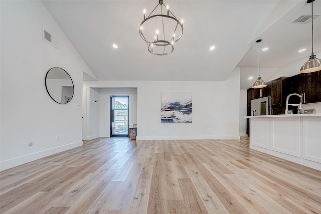 unfurnished living room with a notable chandelier, lofted ceiling, and light wood-type flooring