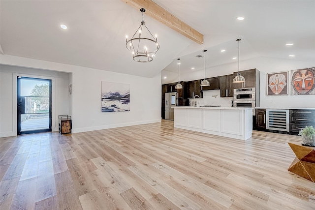 interior space with pendant lighting, vaulted ceiling with beams, light hardwood / wood-style flooring, and beverage cooler