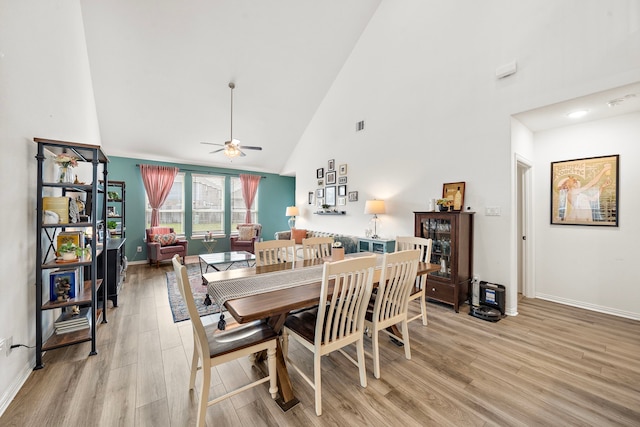 dining room with ceiling fan, high vaulted ceiling, and light hardwood / wood-style flooring