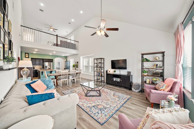 living room featuring ceiling fan, light hardwood / wood-style floors, and high vaulted ceiling