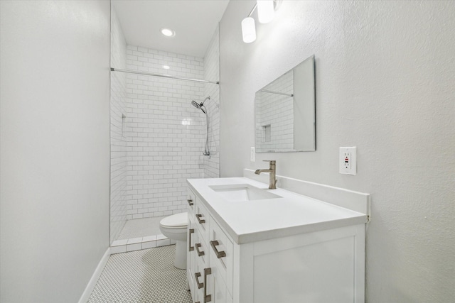 bathroom with tile patterned floors, vanity, toilet, and tiled shower