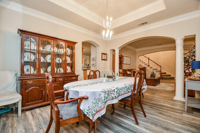 dining area with a chandelier, wood-type flooring, a tray ceiling, and crown molding