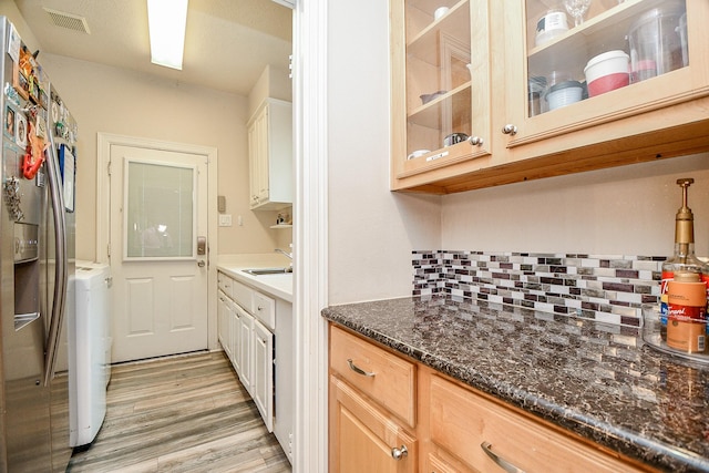 kitchen featuring sink, separate washer and dryer, backsplash, light brown cabinetry, and light wood-type flooring