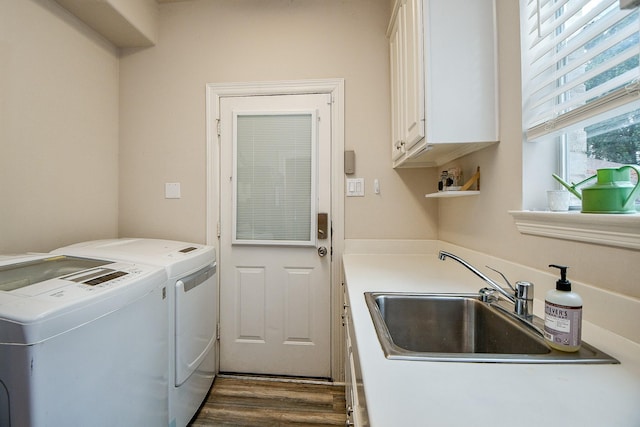 clothes washing area with cabinets, washing machine and clothes dryer, dark wood-type flooring, and sink