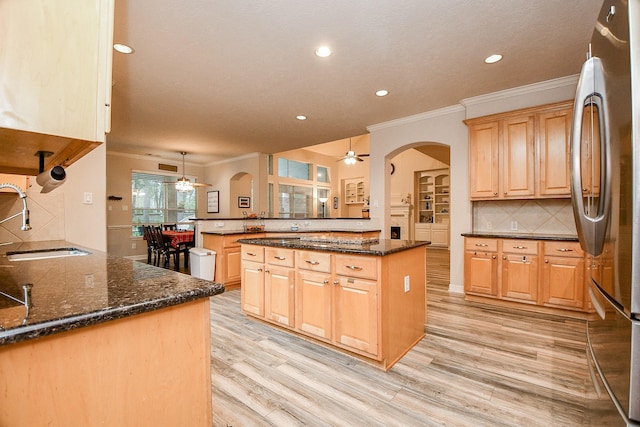 kitchen featuring sink, stainless steel fridge, decorative light fixtures, a kitchen island, and kitchen peninsula