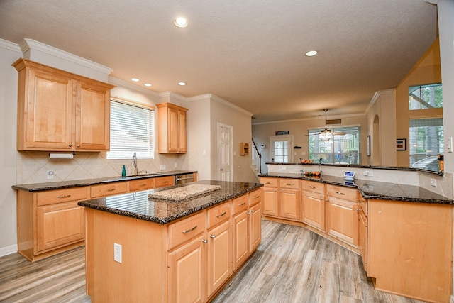 kitchen with sink, hanging light fixtures, kitchen peninsula, a kitchen island, and light wood-type flooring