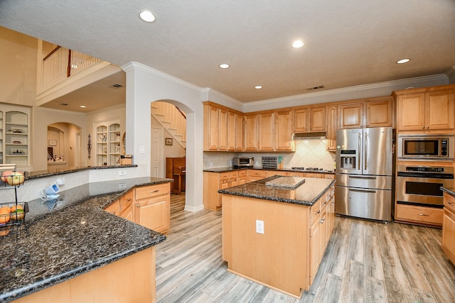 kitchen with dark stone counters, a center island, stainless steel appliances, and light hardwood / wood-style flooring