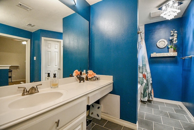 bathroom with tile patterned flooring, a textured ceiling, vanity, and a notable chandelier