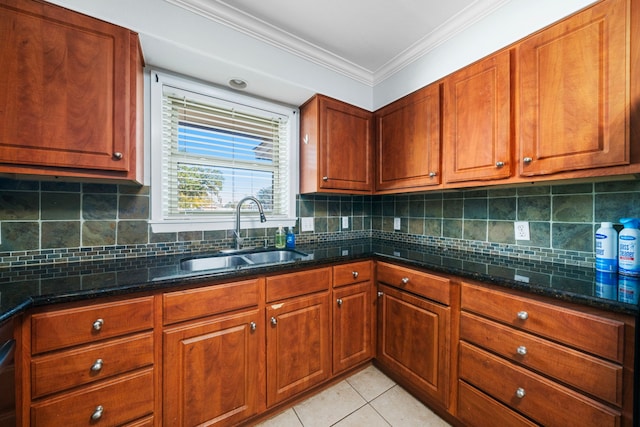 kitchen featuring dark stone countertops, crown molding, sink, and light tile patterned floors