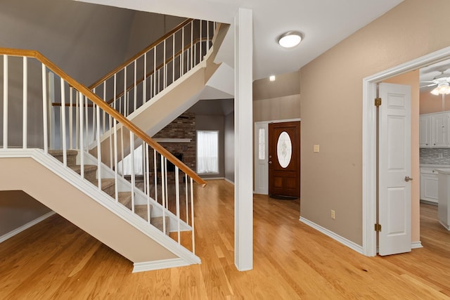 foyer entrance with ceiling fan, a high ceiling, and light hardwood / wood-style flooring