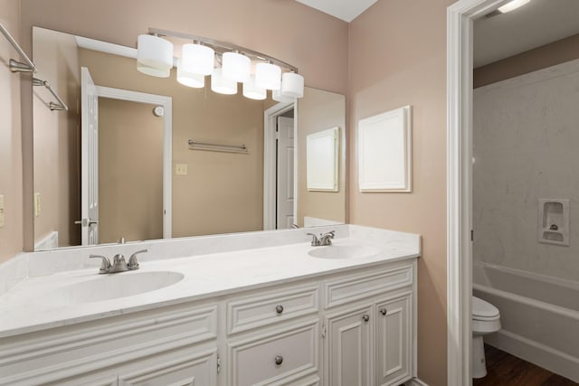 full bathroom featuring hardwood / wood-style floors, vanity, toilet, and shower / tub combination