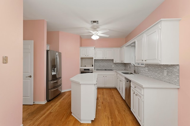 kitchen with a center island, sink, light wood-type flooring, appliances with stainless steel finishes, and white cabinetry