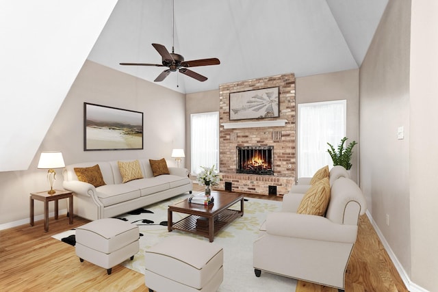 living room with lofted ceiling, a brick fireplace, ceiling fan, and light wood-type flooring