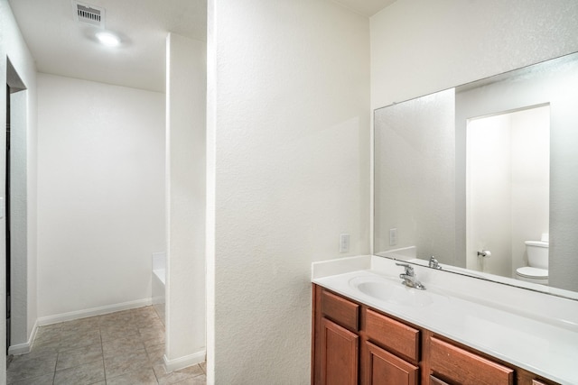 bathroom featuring vanity, a tub to relax in, and toilet