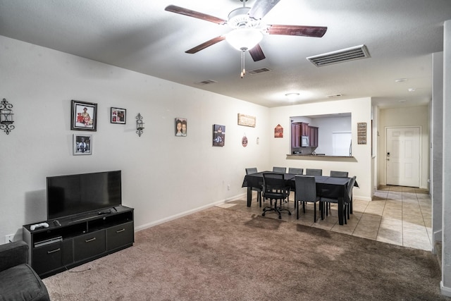 dining room with a textured ceiling, ceiling fan, and light carpet