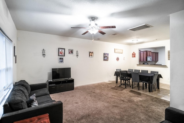 living room with a textured ceiling, ceiling fan, and light carpet