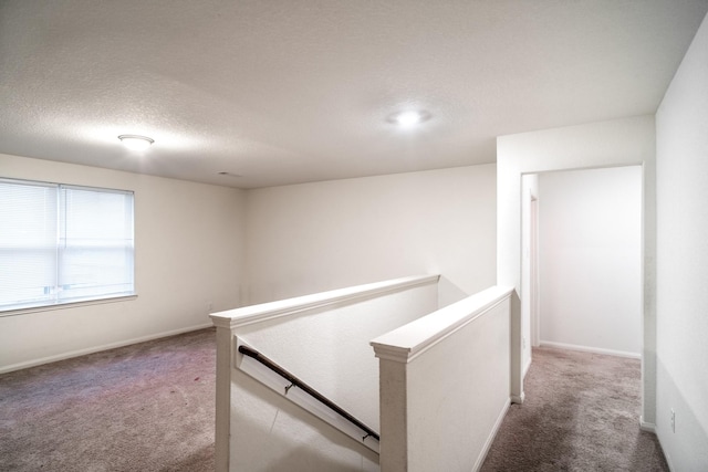 corridor featuring carpet flooring and a textured ceiling